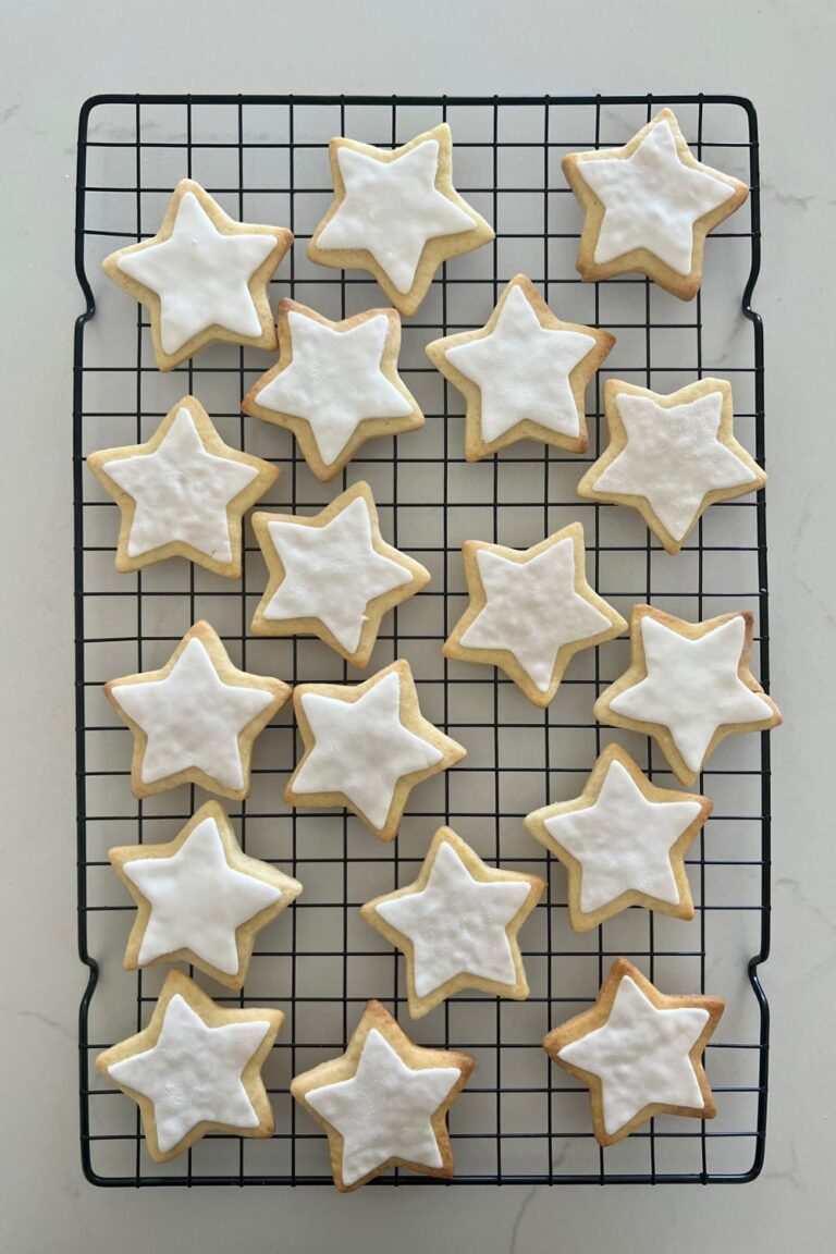 Sourdough sugar cookies decorated with white fondant stars sitting on a black wire rack.