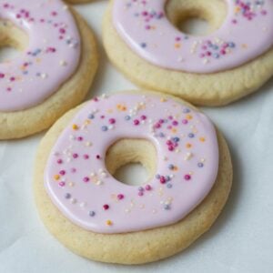 A photo of 3 sourdough sugar cookies that have been decorated to look like little pink donuts.