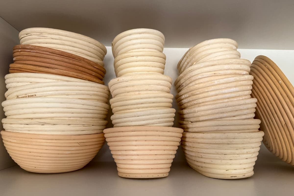 3 stacks of bannetons all pushed together in a cupboard. The bannetons are all different sizes and colors.