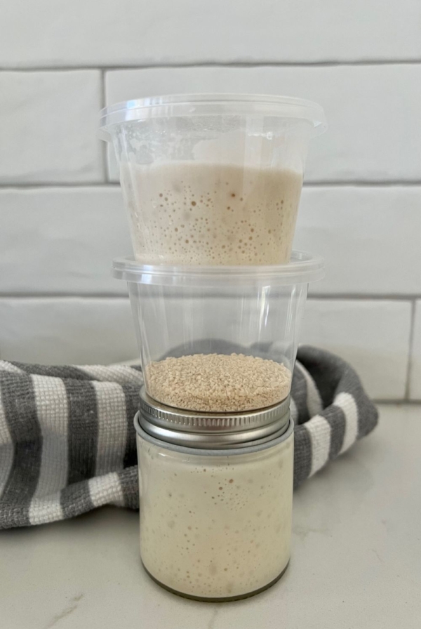 A small mason jar sitting on the counter. There are two small take out containers sitting on top of the mason jar.