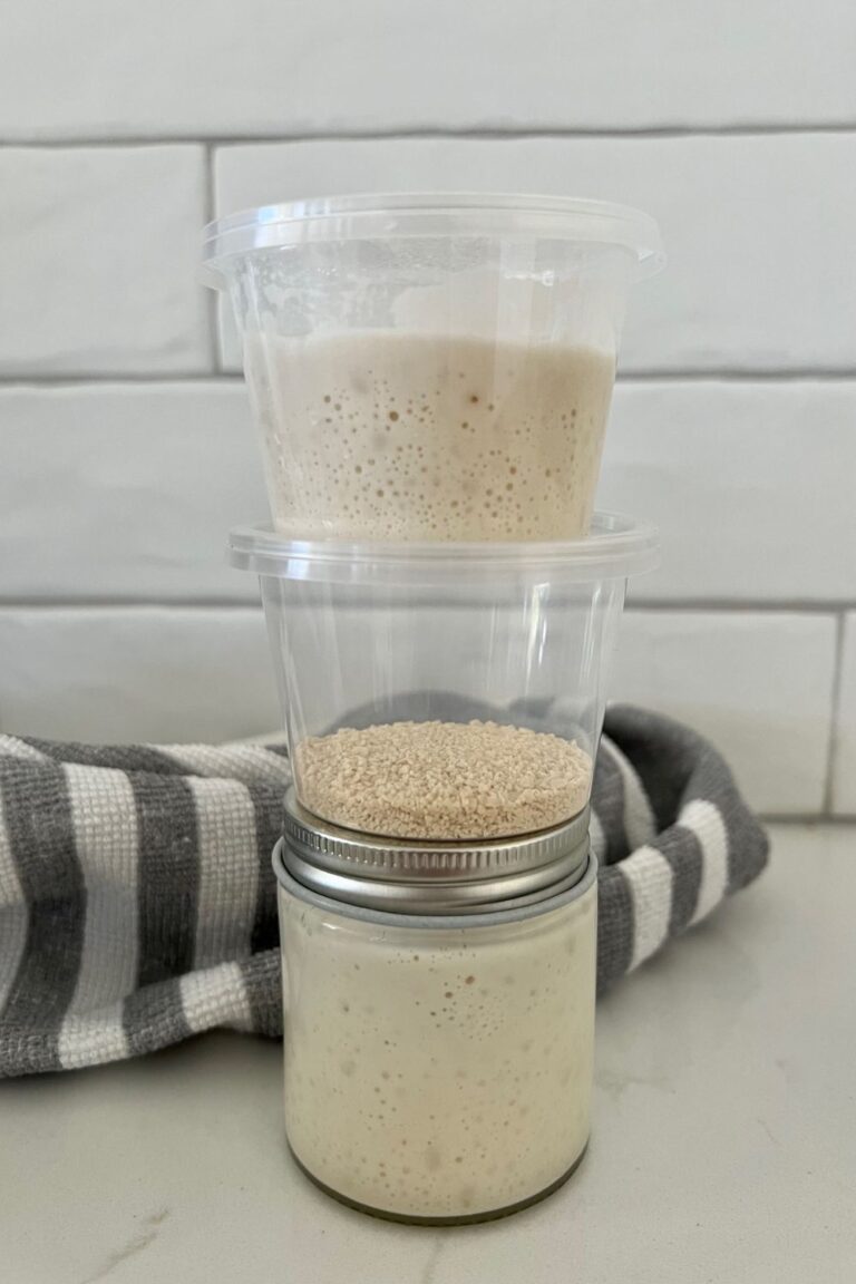 A small mason jar sitting on the counter. There are two small take out containers sitting on top of the mason jar.