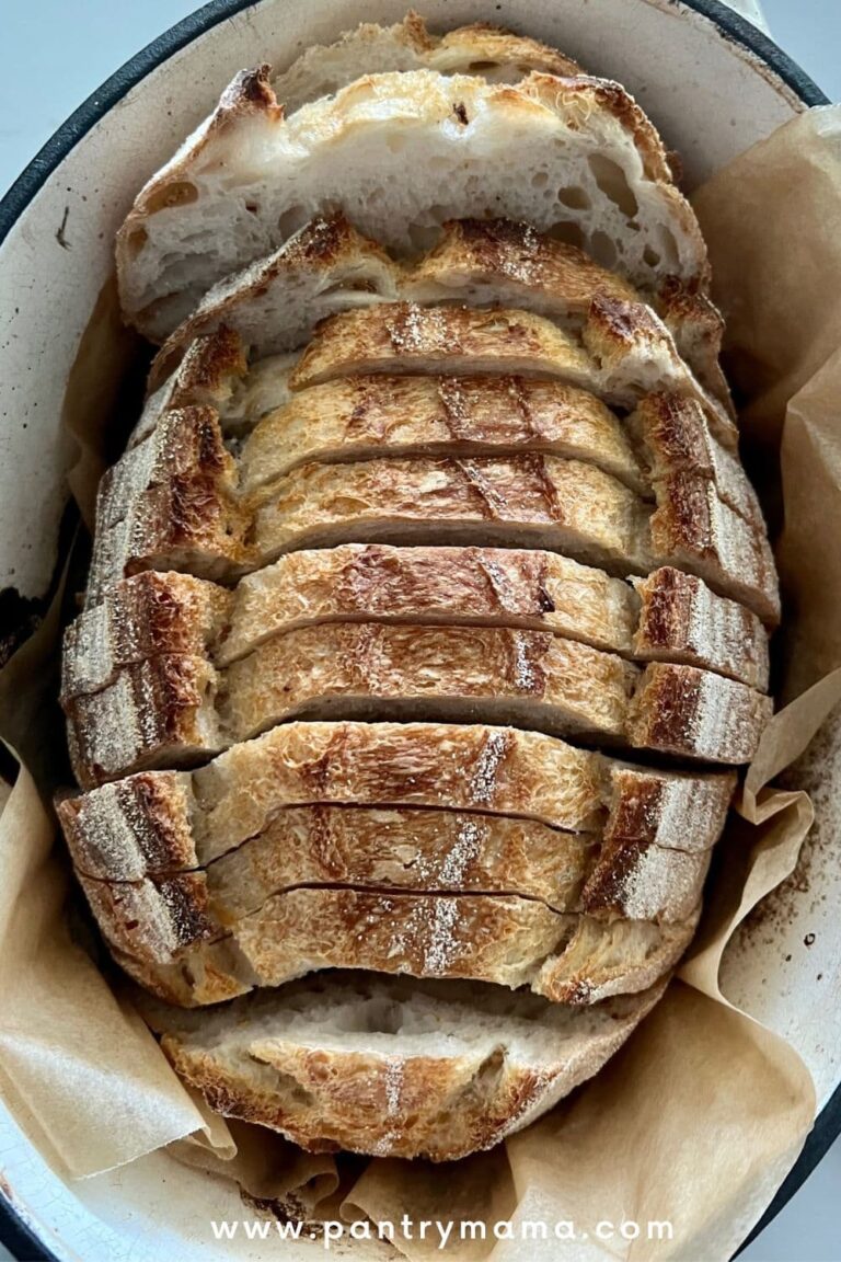 A loaf of overnight sourdough bread that has been sliced and then placed back into an enamel dutch oven.