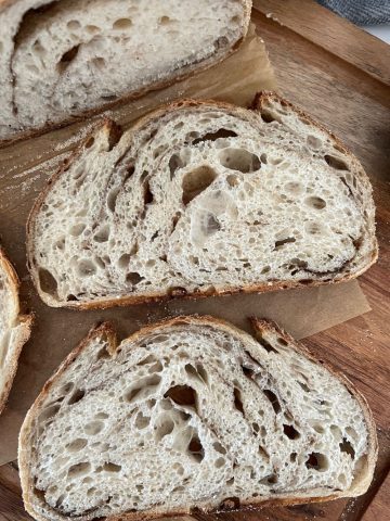 2 slices of Cinnamon Swirl Sourdough Bread sitting on a wooden board.