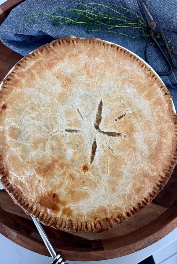 Sourdough chicken pot pie sitting in a wooden tray with a bunch of thyme next to it.