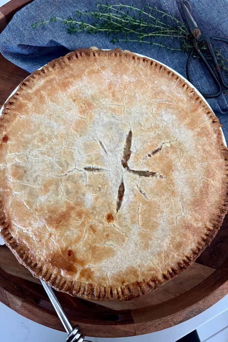 Sourdough chicken pot pie sitting in a wooden tray with a bunch of thyme next to it.