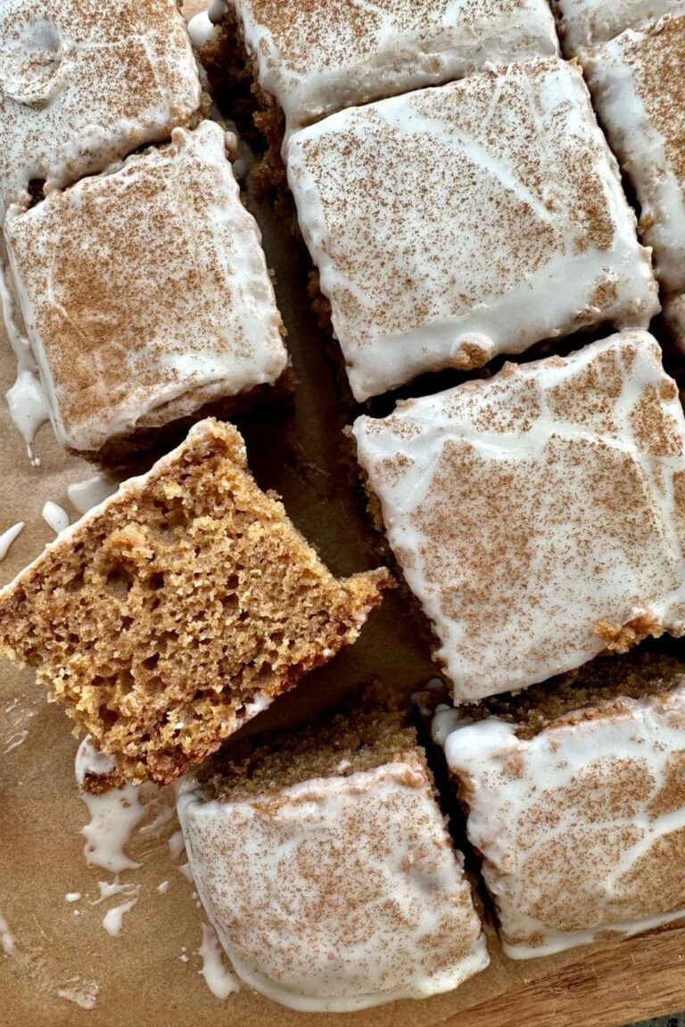 Sourdough Applesauce Cake covered in yogurt glaze and cinnamon. There is a piece of the cake that is laid on its side so you can see the texture.