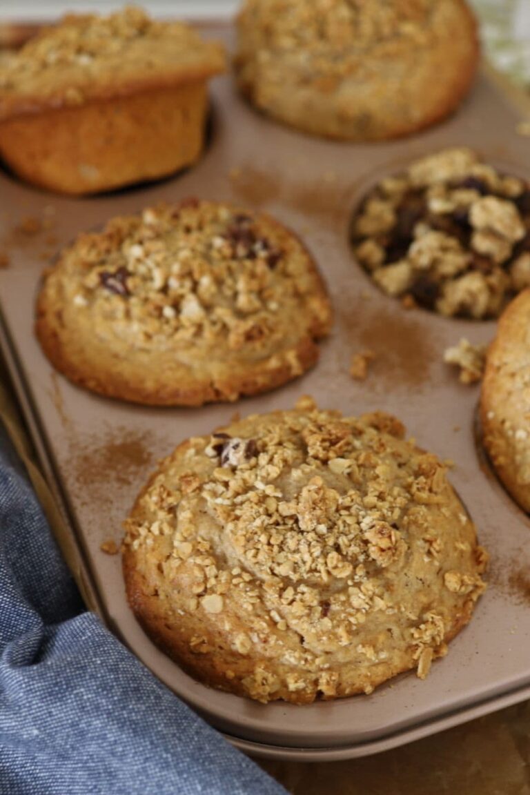 JUMBO SOURDOUGH GRANOLA MUFFINS - FEATURE IMAGE Sourdough Granola Muffins are sitting in a giant 6 hole muffin tin with a blue dish towel in the foreground.