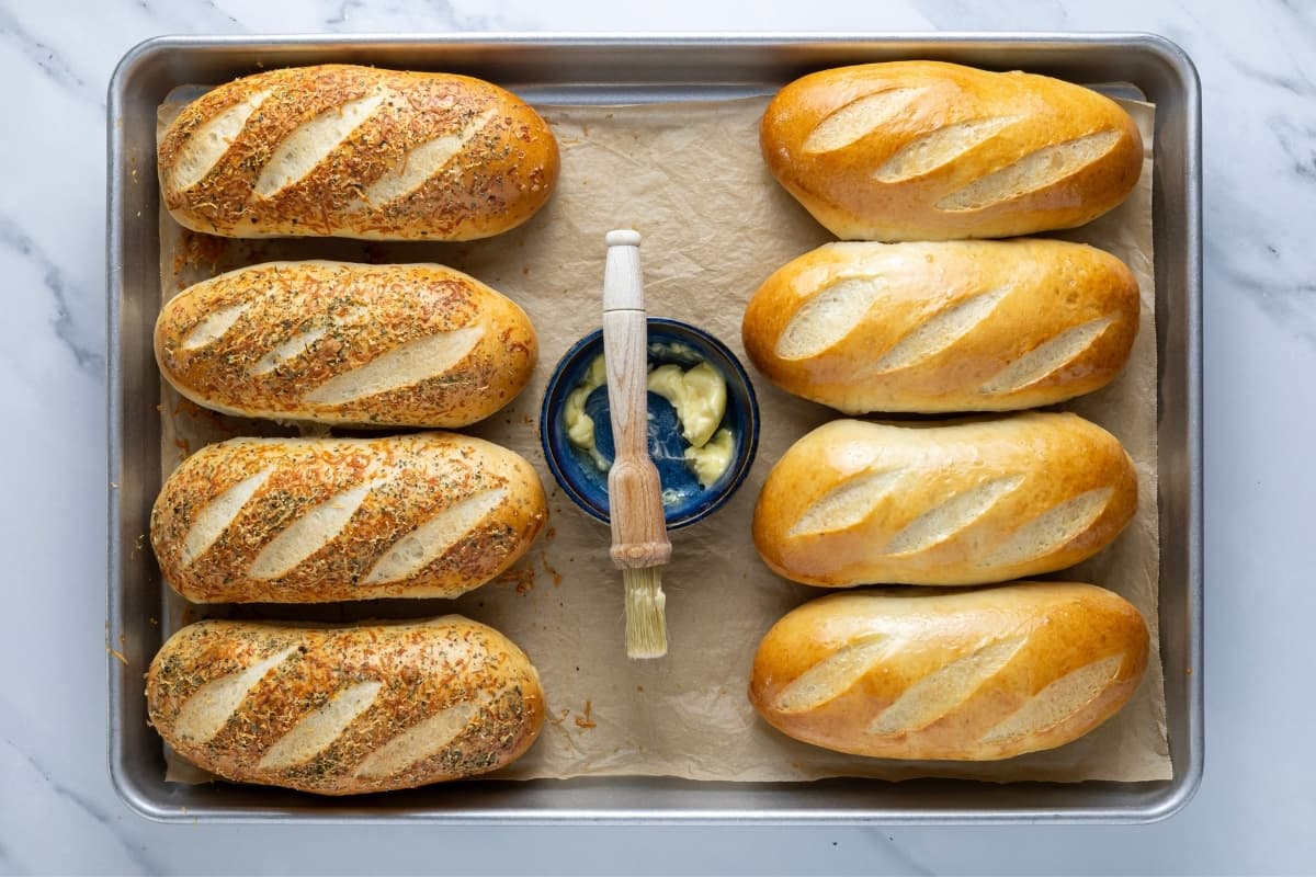 Brushing fresh baked sourdough sandwich rolls with butter.
