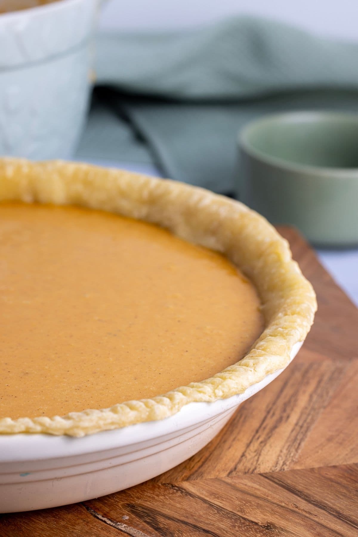 A close up image of the pie crust filled with orange pumpkin pie filling.