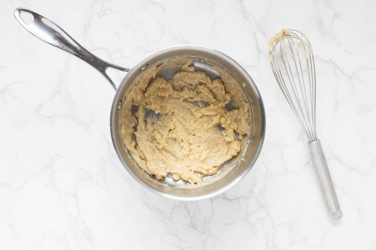 A saucepan showing a roux made with butter and sourdough discard that have been whisked together.
