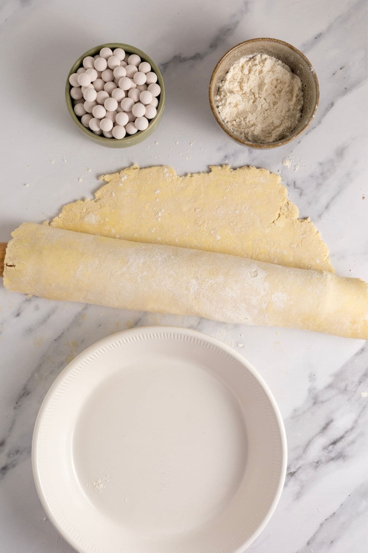 The pastry has been rolled around the rolling pin to make it easier to lift into the pie dish. You can see the empty pie plate waiting to receive the sourdough pastry.