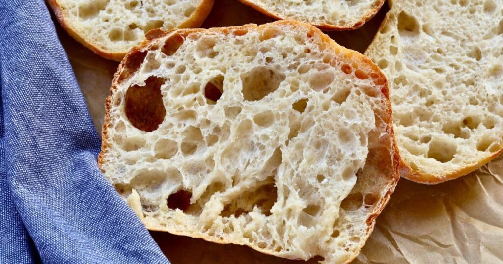 Sourdough cibatta roll that has been sliced open to reveal the open crumb structure inside.