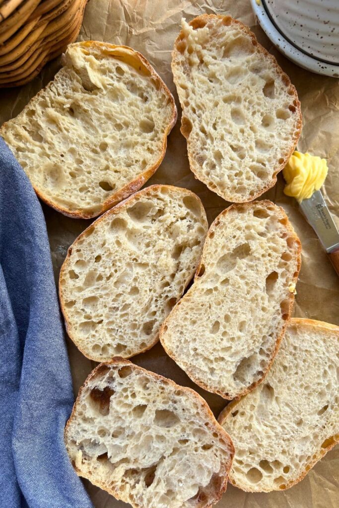 Sourdough cibatta roll that has been sliced open to reveal the open crumb structure inside.