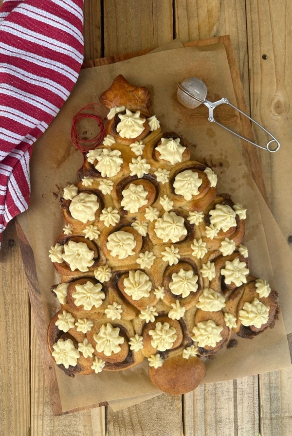 Sourdough cinnamon rolls baked in the shape of a Christmas Tree pull apart loaf. The cinnamon rolls have been iced with cream cheese Christmas stars.