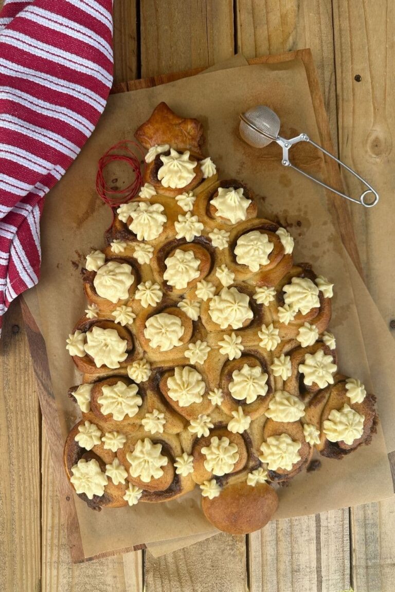 Sourdough cinnamon rolls baked in the shape of a Christmas Tree pull apart loaf. The cinnamon rolls have been iced with cream cheese Christmas stars.