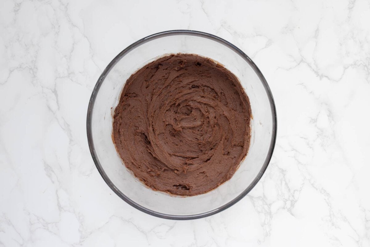 A glass bowl containing the sourdough chocolate cookie dough required to make crinkle cookies