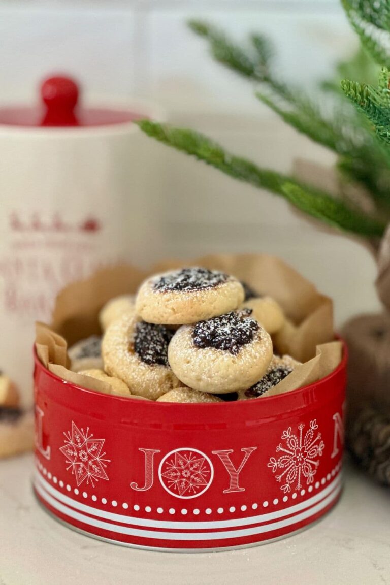 Sourdough fruit mince thumbprint cookies sitting in a red cookie tin with the word "joy" written on the front.