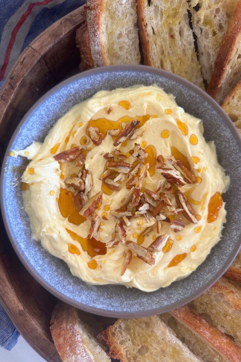 A bowl of whipped Brie butter drizzled in honey and pecans and served with sourdough Crostini.