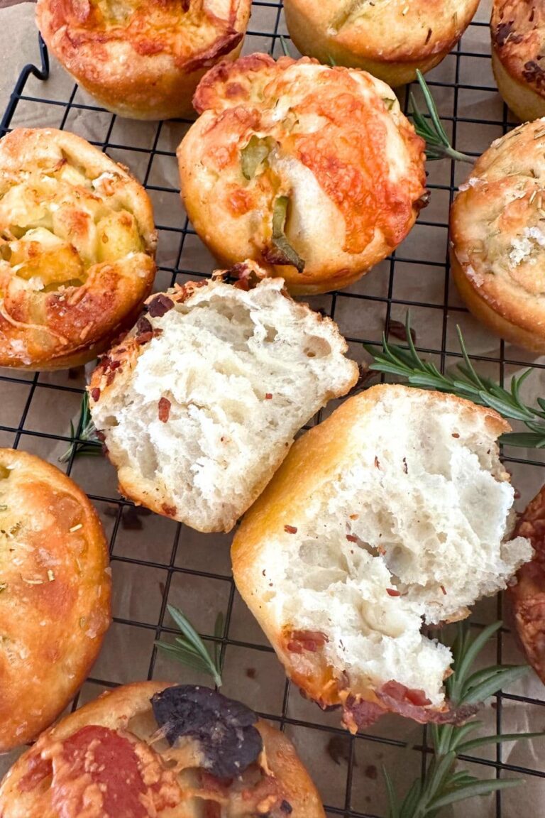 Sourdough focaccia bread muffins arranged on a black wire cooling rack.