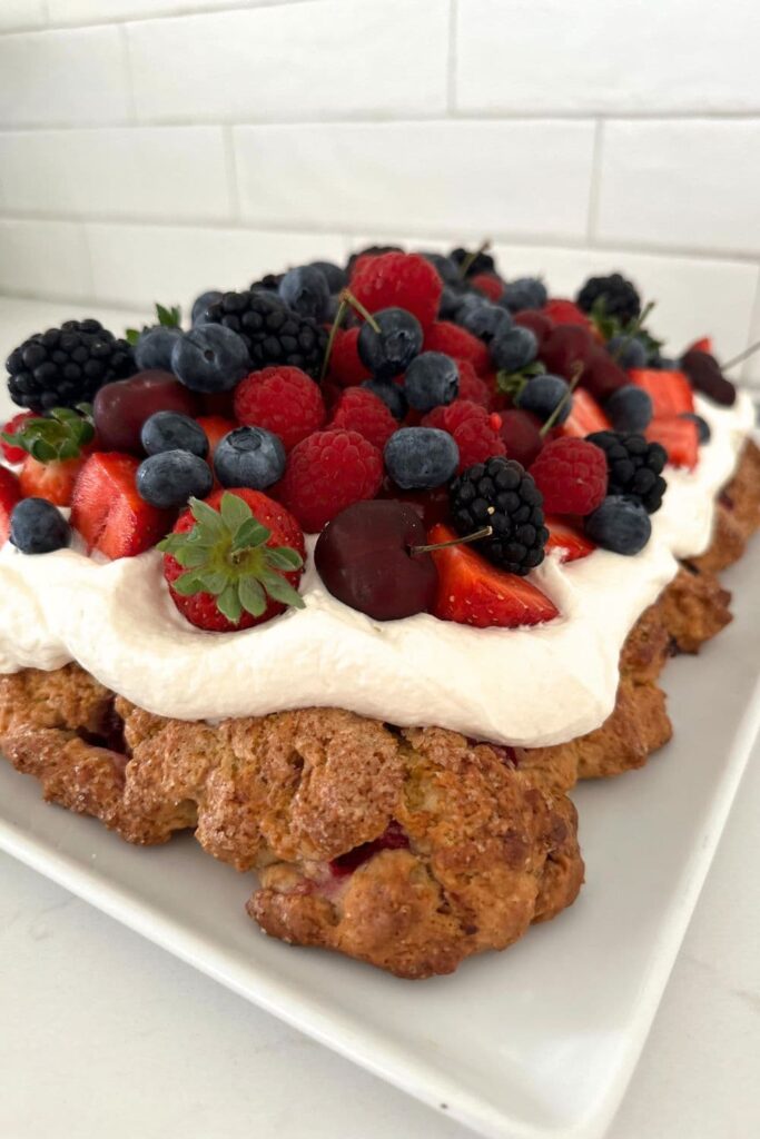 Sourdough berry sheet pan shortcake topped with whipped cream and berries.