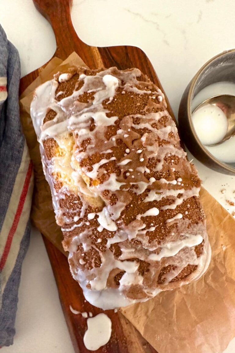 A loaf of sourdough discard cinnamon ripple quick bread on a wooden serving platter.