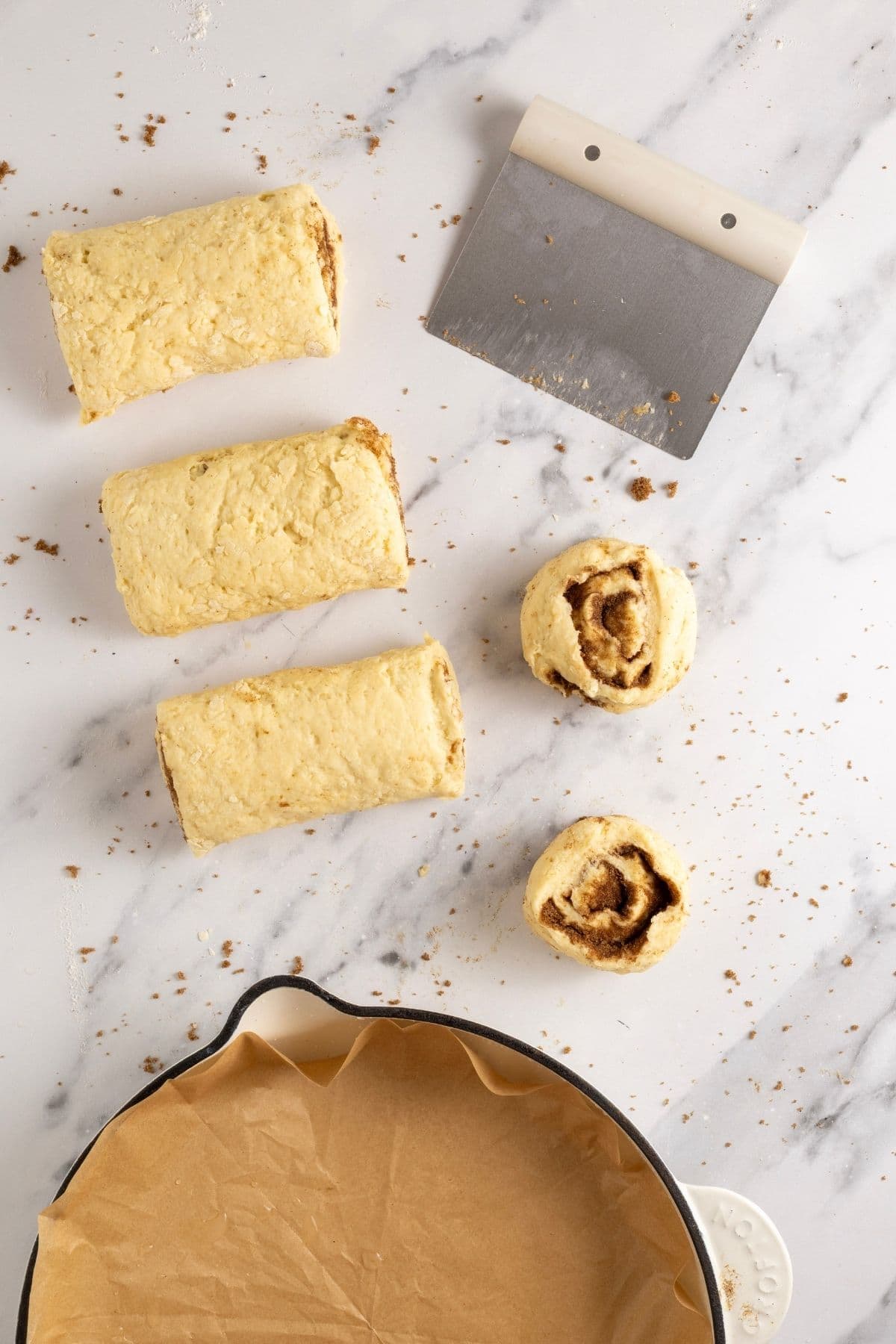 An image showing the log being divided into 4 equal pieces and then divided again into 8 individual cinnamon rolls.