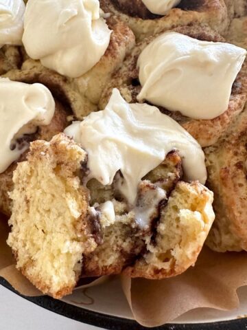A close up photo of the fluffy and soft interior of no wait sourdough cinnamon rolls showing the decadent cinnamon filling and creamy vanilla cream cheese frosting.