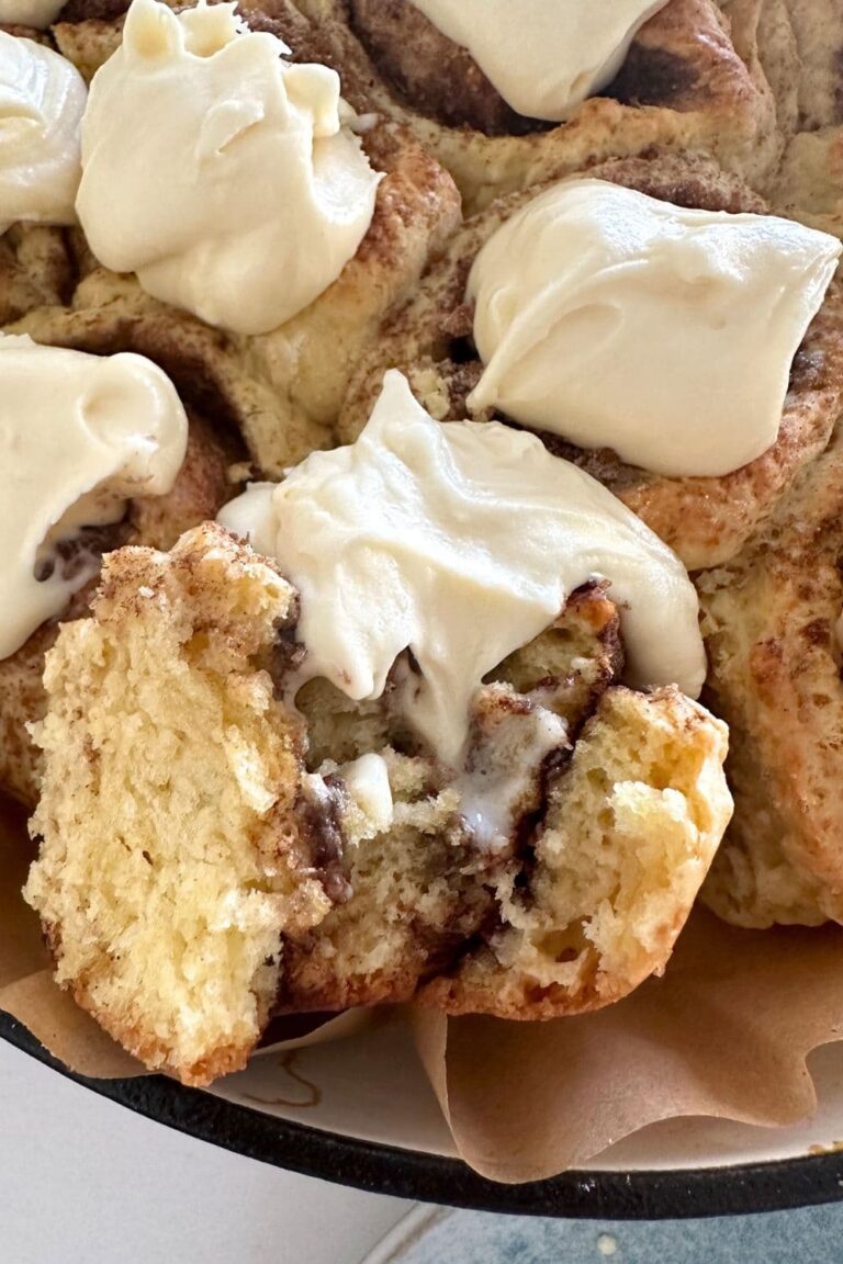 A close up photo of the fluffy and soft interior of no wait sourdough cinnamon rolls showing the decadent cinnamon filling and creamy vanilla cream cheese frosting.