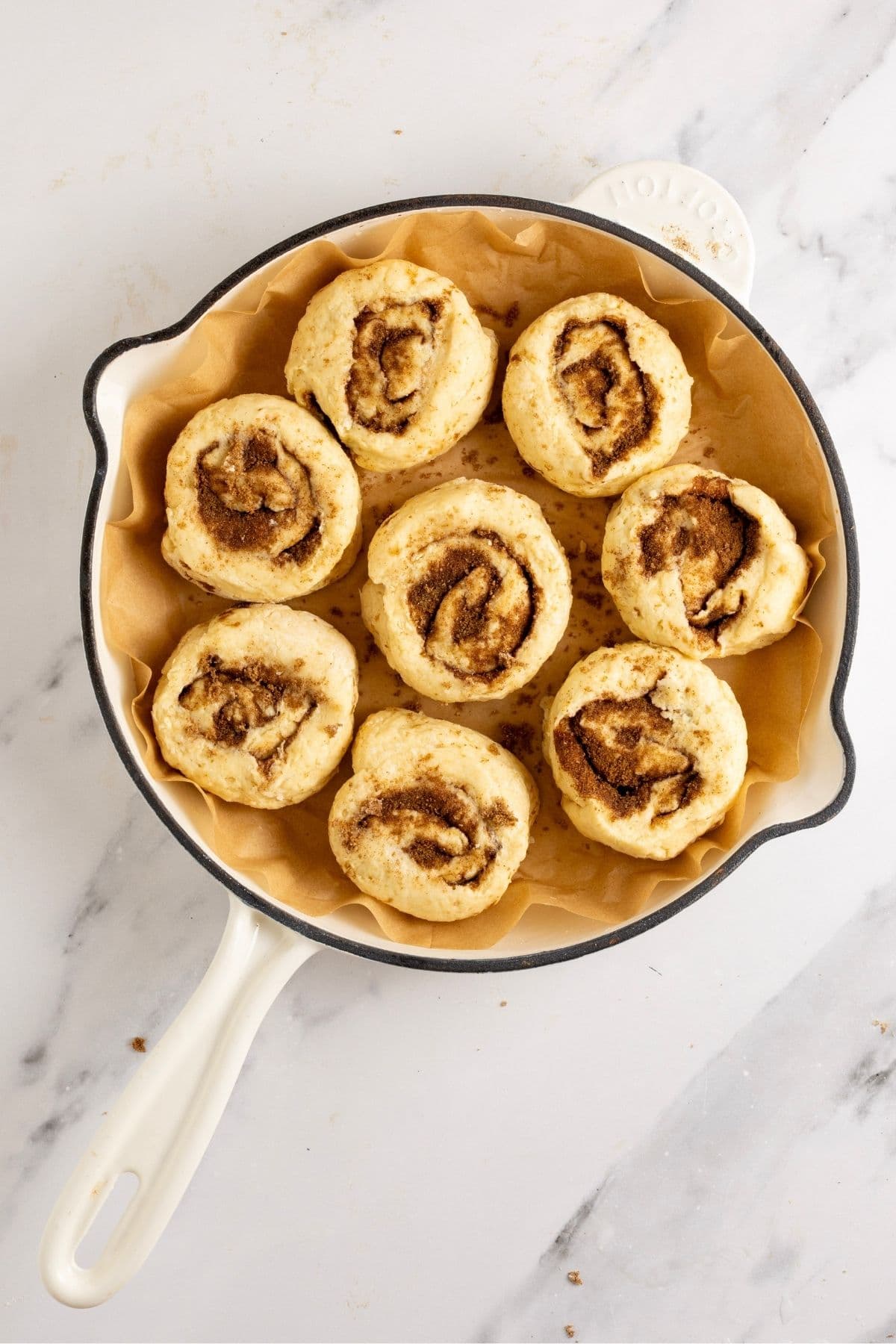 8 sourdough discard cinnamon rolls placed into a 10" cast-iron skillet ready to go into the oven.