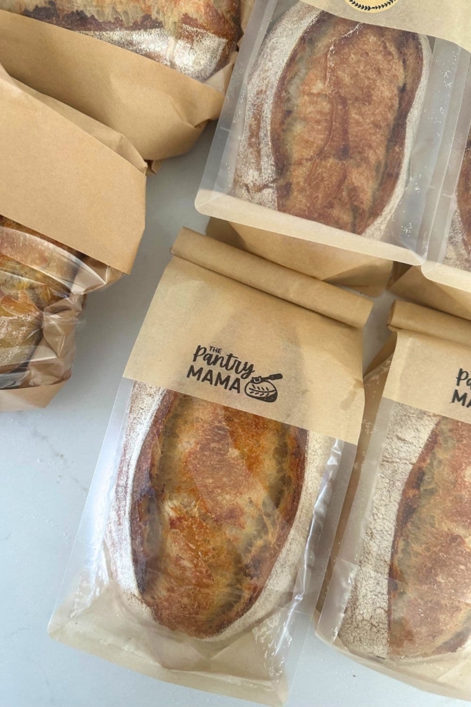 Loaves of sourdough bread in paper & plastic bags labelled "The Pantry Mama".