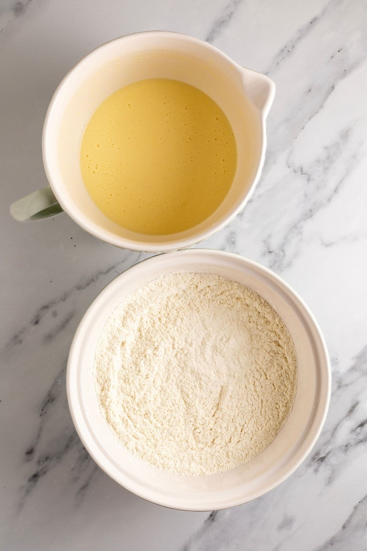 Image showing the wet ingredients in a cream batter jug and dry ingredients whisked together in a bowl.