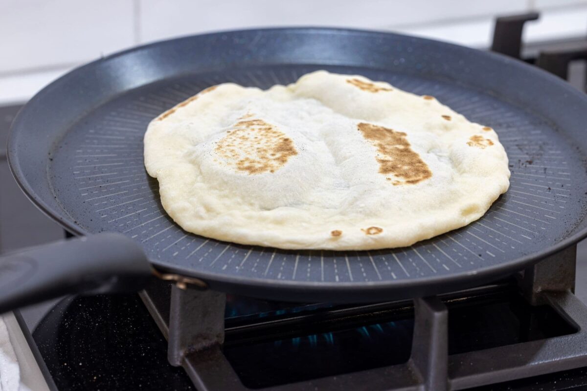 A bubbly sourdough discard tortilla being cooked on a nonstick crepe pan.