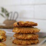 Stack of 4 sourdough cornflake raisin cookies taken in front of a white tiled wall.