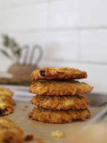 Stack of 4 sourdough cornflake raisin cookies taken in front of a white tiled wall.