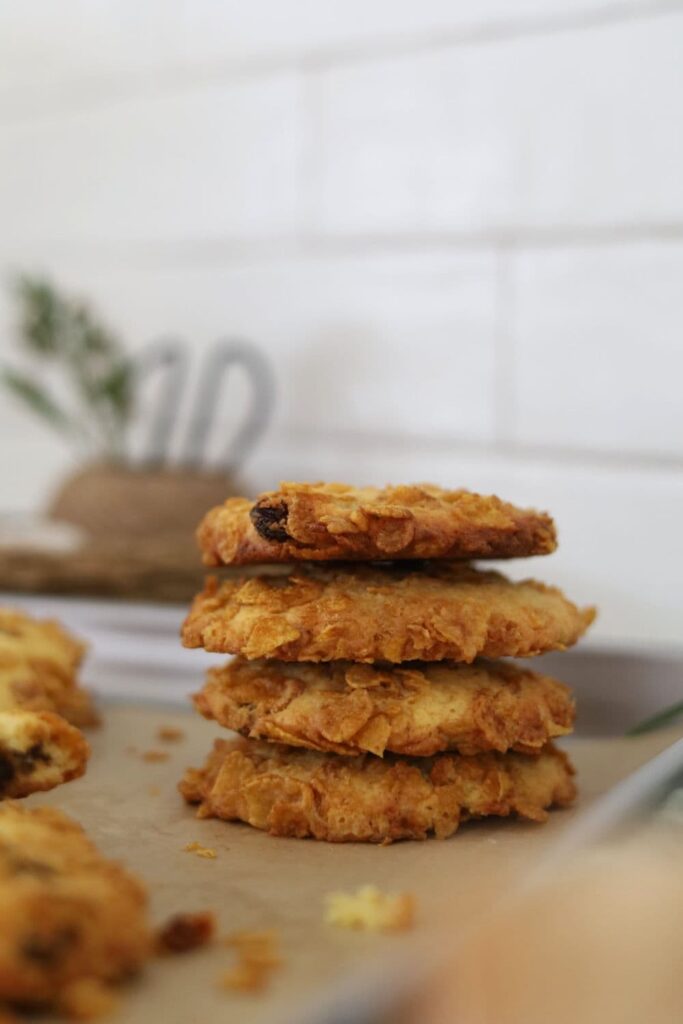 Stack of 4 sourdough cornflake raisin cookies taken in front of a white tiled wall.