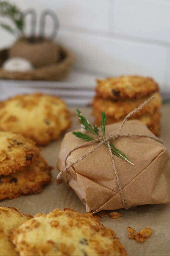 Sourdough cornflake raisin cookies wrapped in baking paper and tied with some string and a little stem of white flowers.