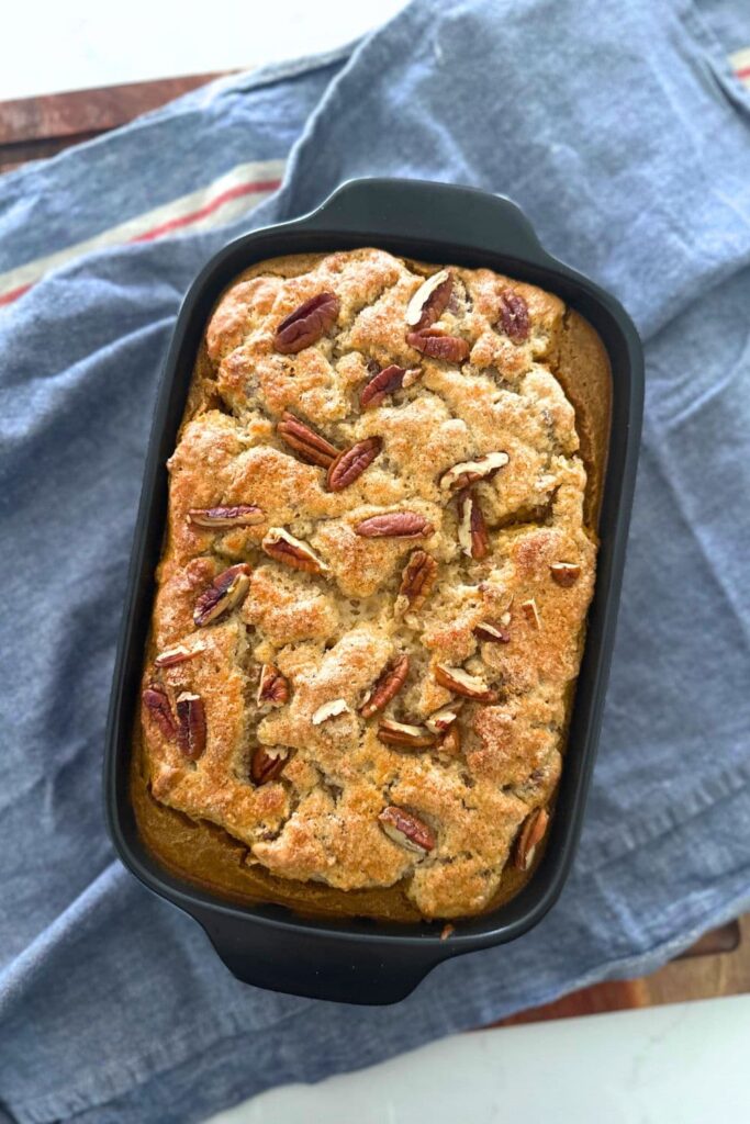 A grey baking dish containing a sourdough pumpkin pecan cobbler that has just been removed from the oven.