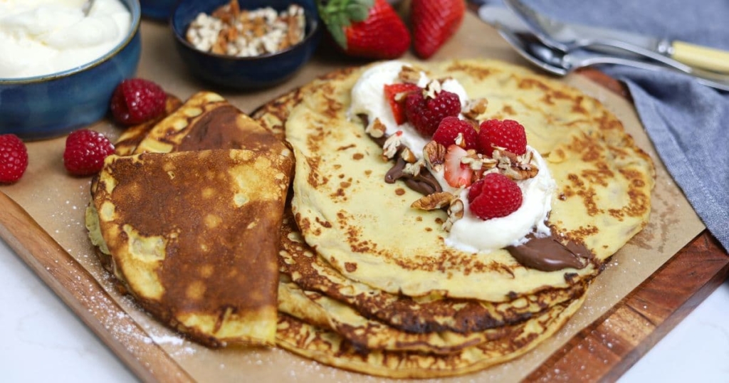 A display of sourdough discard crepes topped with nutella, whipped cream and berries.