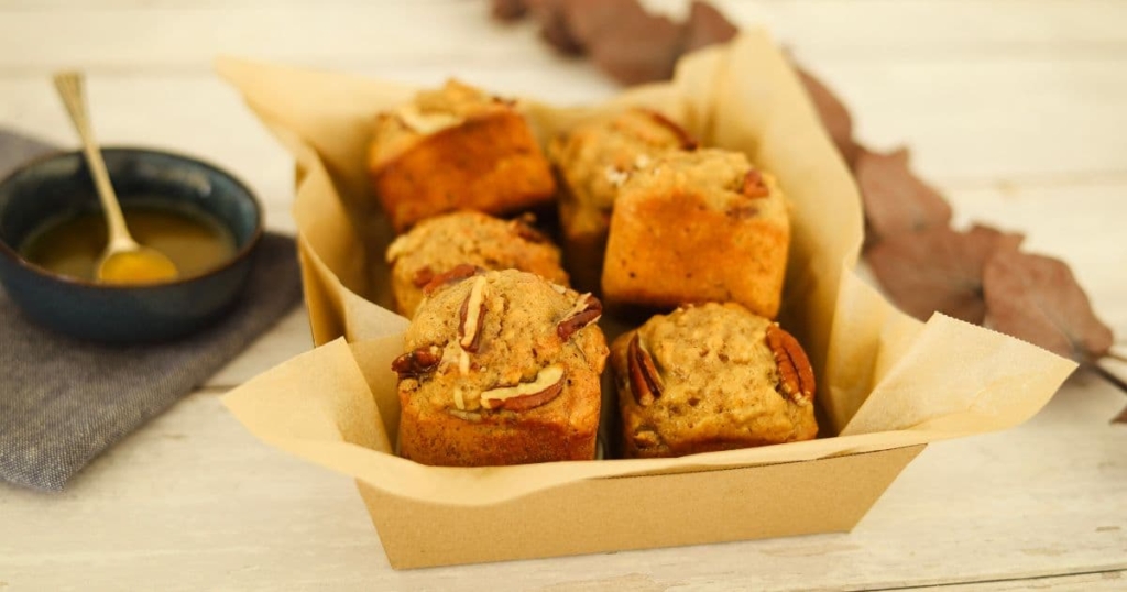 A tray of maple pecan sourdough muffins that have been baked in a square muffin pan. There is a dish of maple butter syrup next to the muffins.