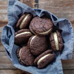 SOURDOUGH CHOCOLATE SANDWICH COOKIES sitting in a blue dish towel on a wooden counter top.