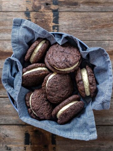 SOURDOUGH CHOCOLATE SANDWICH COOKIES sitting in a blue dish towel on a wooden counter top.