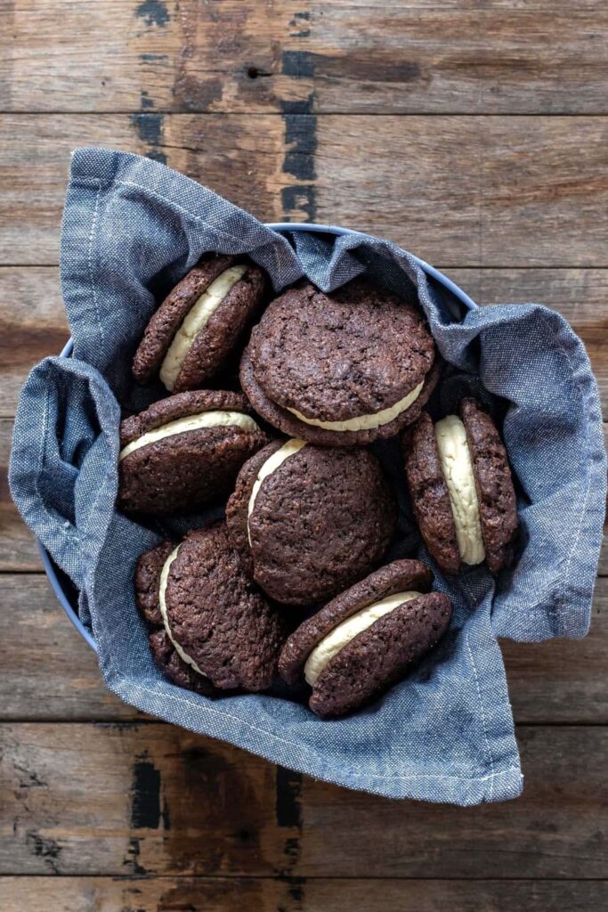 SOURDOUGH CHOCOLATE SANDWICH COOKIES sitting in a blue dish towel on a wooden counter top.