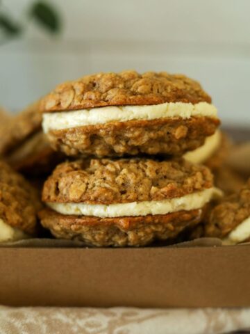 A close up of 2 sourdough oatmeal cream pies filled with vanilla cream filling.