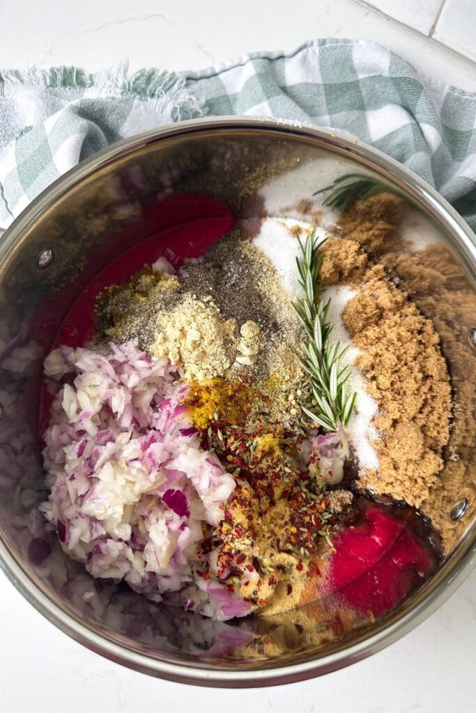 All of the ingredients necessary to make chilli tomato relish layered in a stainless steel pot.