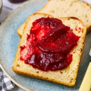 A slice of sourdough bread spread with cranberry orange jam, also known as Thanksgiving jam.