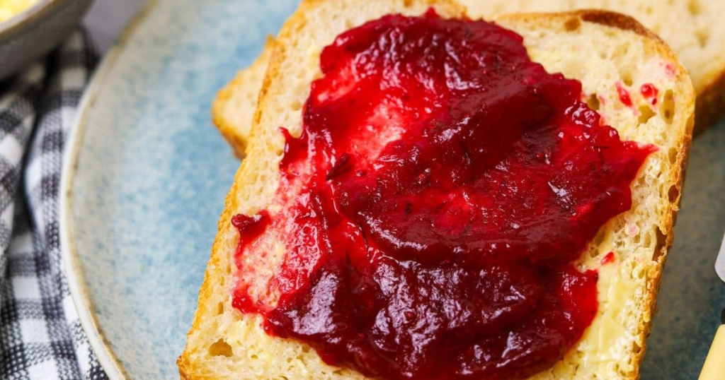 A slice of sourdough bread spread with cranberry orange jam.