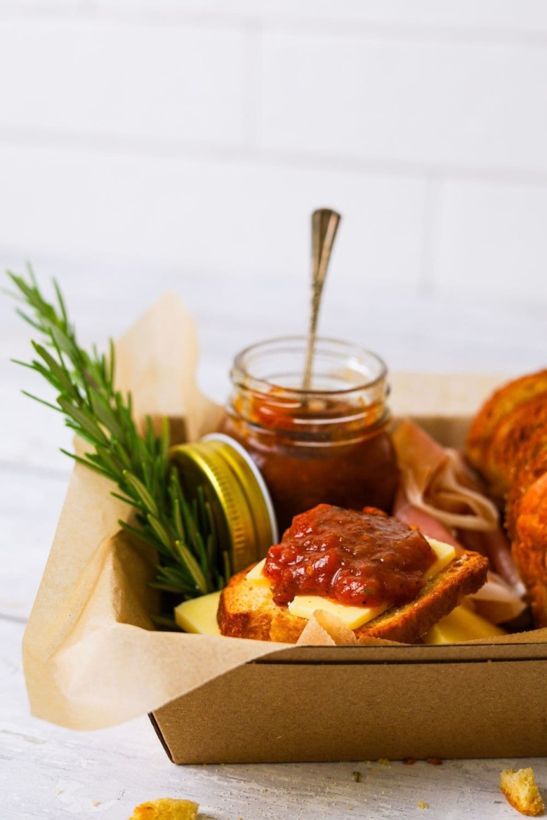 A jar of tomato chutney displayed with sourdough crostini.