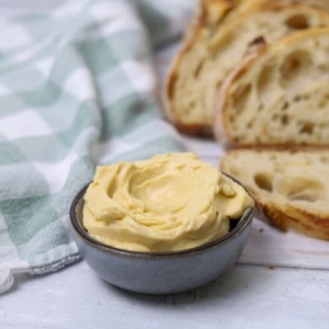 A small bowl of whipped maple butter sitting nestled among slices of sourdough bread.