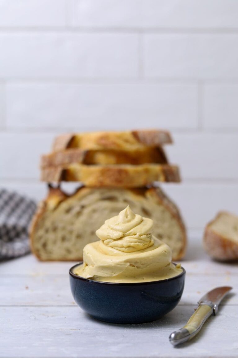 A small blue bowl filled to overflowing with whipped maple butter. You can see a loaf of sourdough bread in the background.