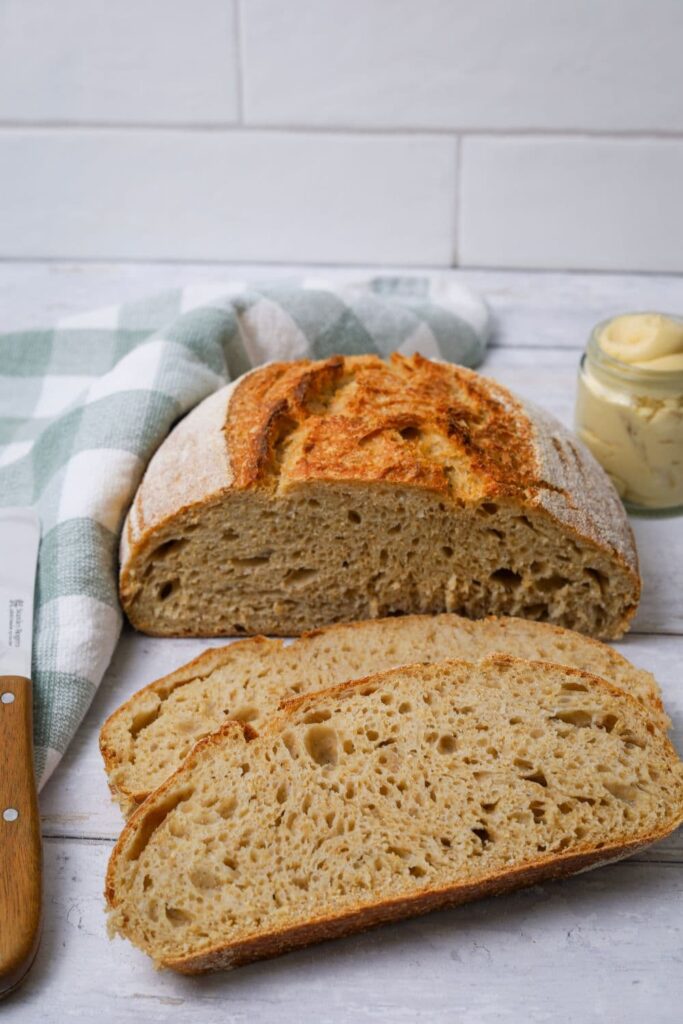 Slices of whole wheat sourdough bread laid out on a white wooden board.